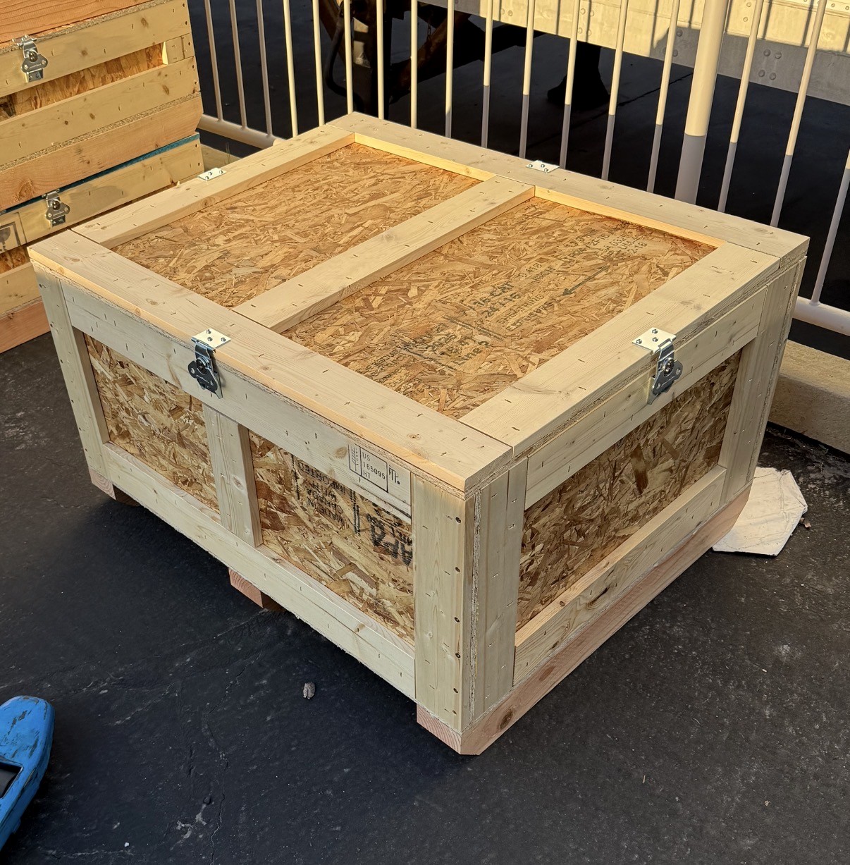 Close-up view of a heavy-duty framed OSB crate with metal latches